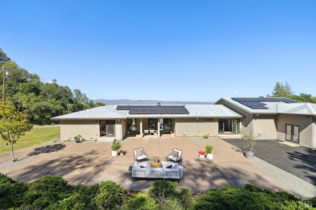 back of property with an outdoor living space, french doors, solar panels, a patio area, and stucco siding