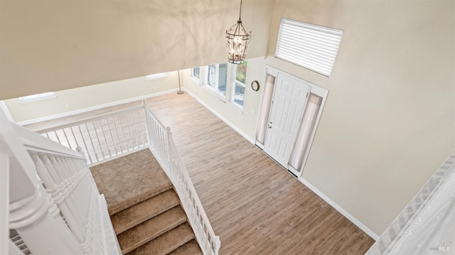 foyer entrance featuring an inviting chandelier, wood finished floors, and baseboards
