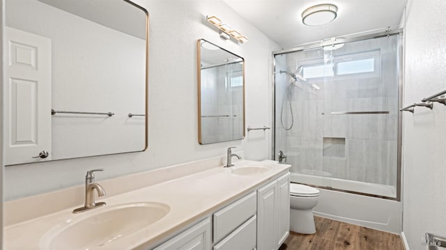 full bathroom with double vanity, toilet, wood finished floors, and a sink