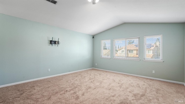 carpeted empty room with lofted ceiling, baseboards, and visible vents
