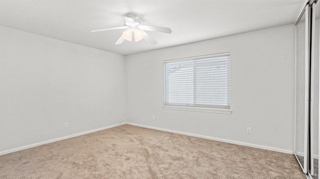 carpeted empty room featuring baseboards and ceiling fan