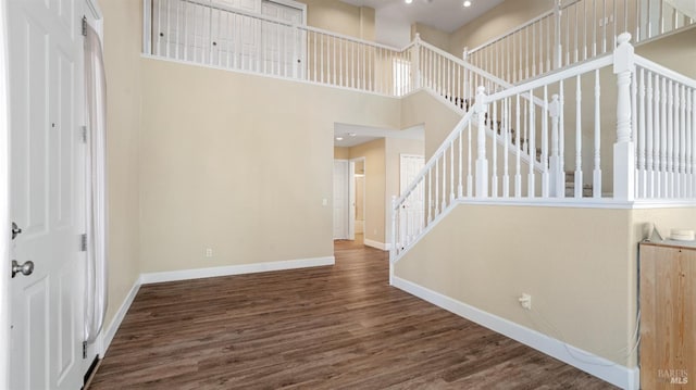 interior space with stairway, a towering ceiling, baseboards, and wood finished floors