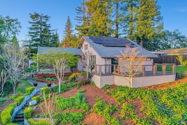 rear view of property with solar panels, fence, a shingled roof, and a chimney