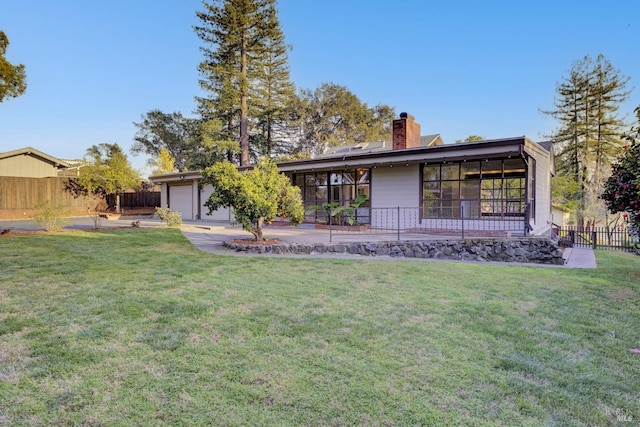 rear view of house with a yard, fence, a garage, and a chimney