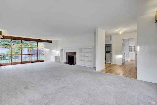 unfurnished living room featuring baseboards, a fireplace, and carpet flooring