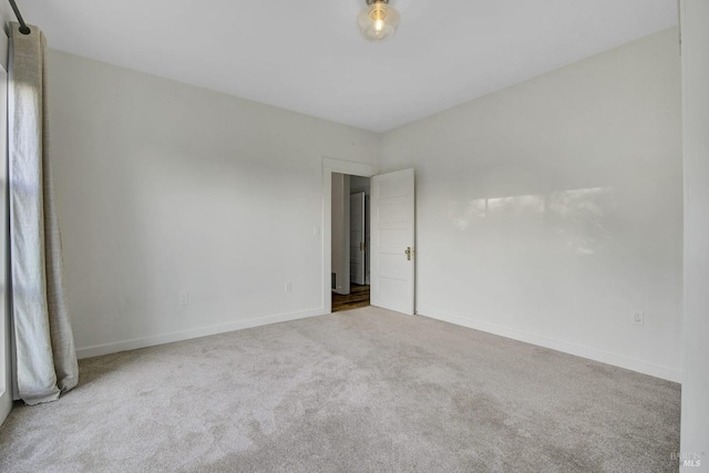 carpeted empty room featuring baseboards