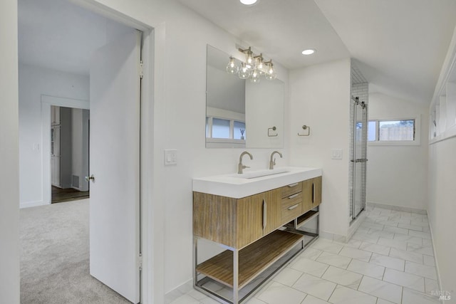 full bath featuring a shower stall, baseboards, double vanity, vaulted ceiling, and a sink