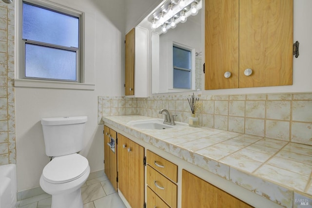 full bath featuring vanity, baseboards, decorative backsplash, toilet, and a bathtub