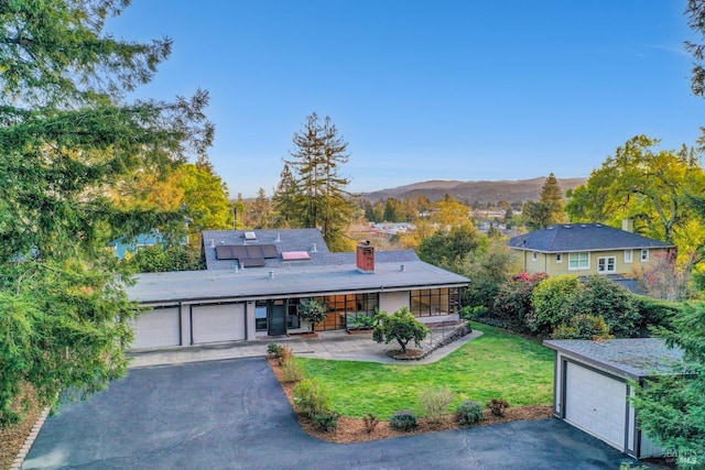 view of front of house with a front lawn, roof mounted solar panels, a porch, a mountain view, and a chimney