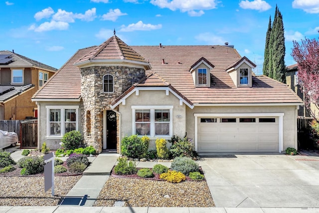view of front facade featuring stucco siding, a tile roof, fence, concrete driveway, and a garage