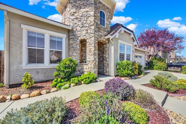exterior space with stone siding, stucco siding, and an attached garage