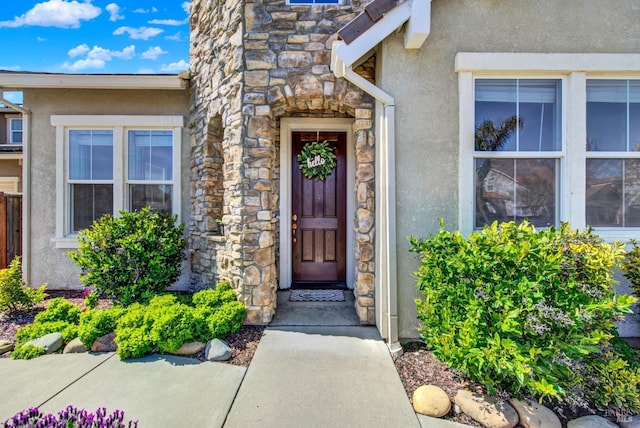 doorway to property featuring stucco siding and stone siding