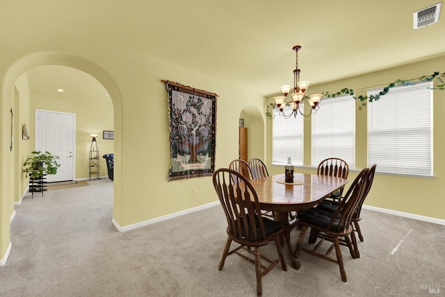 dining area with visible vents, baseboards, carpet floors, an inviting chandelier, and arched walkways