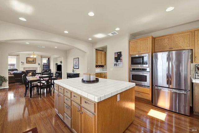 kitchen featuring arched walkways, visible vents, stainless steel appliances, and tile counters