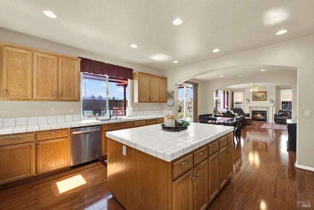 kitchen featuring a kitchen island, tile countertops, dishwasher, dark wood-style floors, and a sink