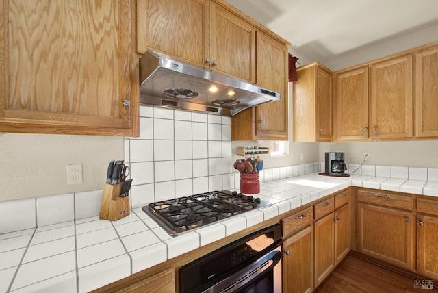 kitchen featuring under cabinet range hood, tile countertops, and stainless steel appliances