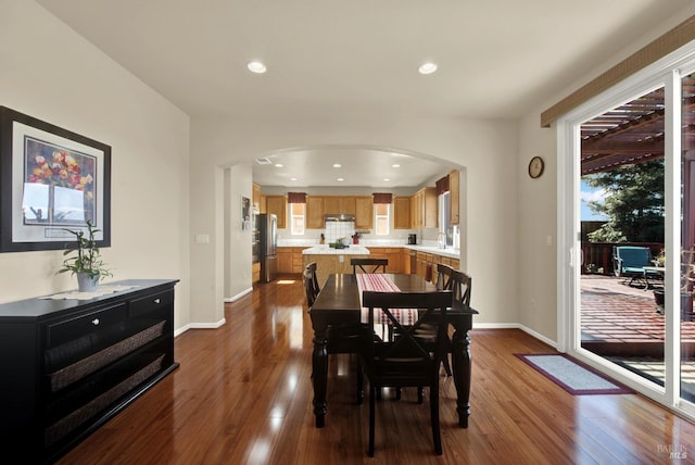 dining room featuring recessed lighting, baseboards, arched walkways, and dark wood-style floors
