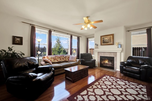 living area with ceiling fan, wood finished floors, and a tiled fireplace