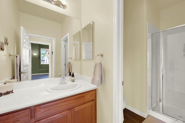 bathroom with baseboards, toilet, a stall shower, and vanity