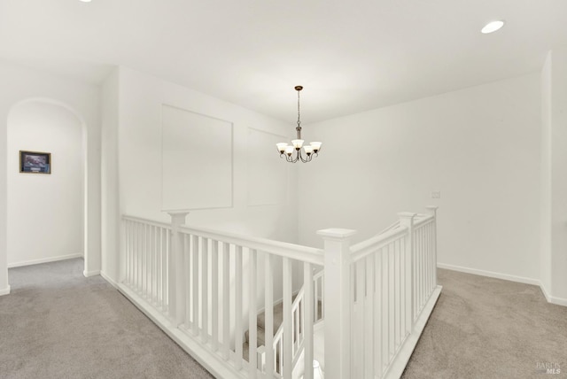 hall featuring baseboards, recessed lighting, light carpet, a notable chandelier, and an upstairs landing