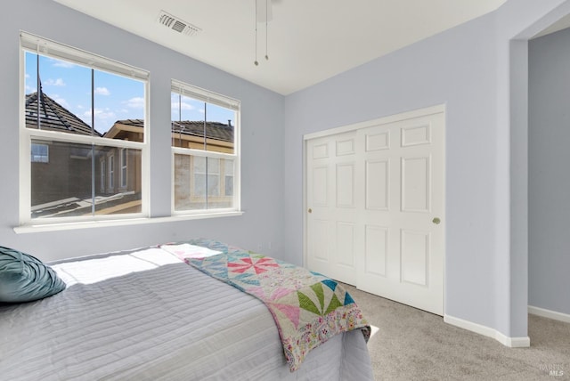 carpeted bedroom featuring visible vents, baseboards, and a closet