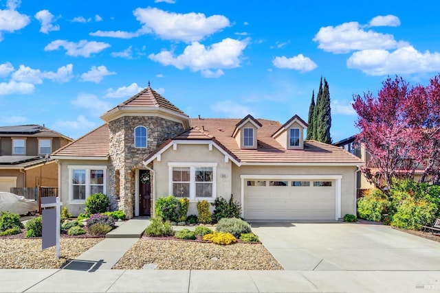 traditional-style home featuring concrete driveway, a tile roof, stucco siding, a garage, and stone siding