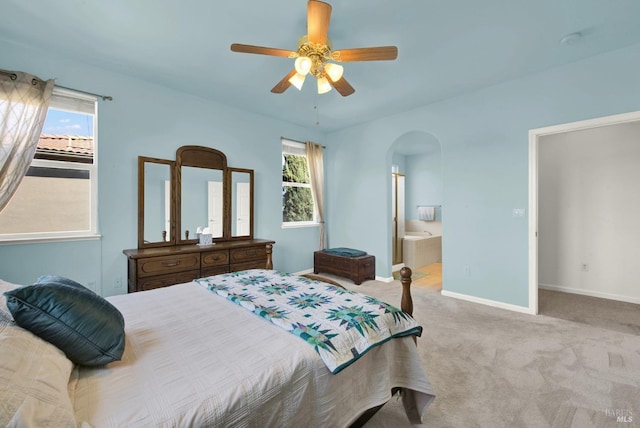 bedroom featuring connected bathroom, ceiling fan, baseboards, carpet flooring, and arched walkways