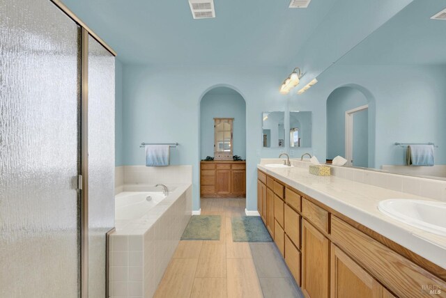 full bath featuring a sink, visible vents, a bath, and double vanity