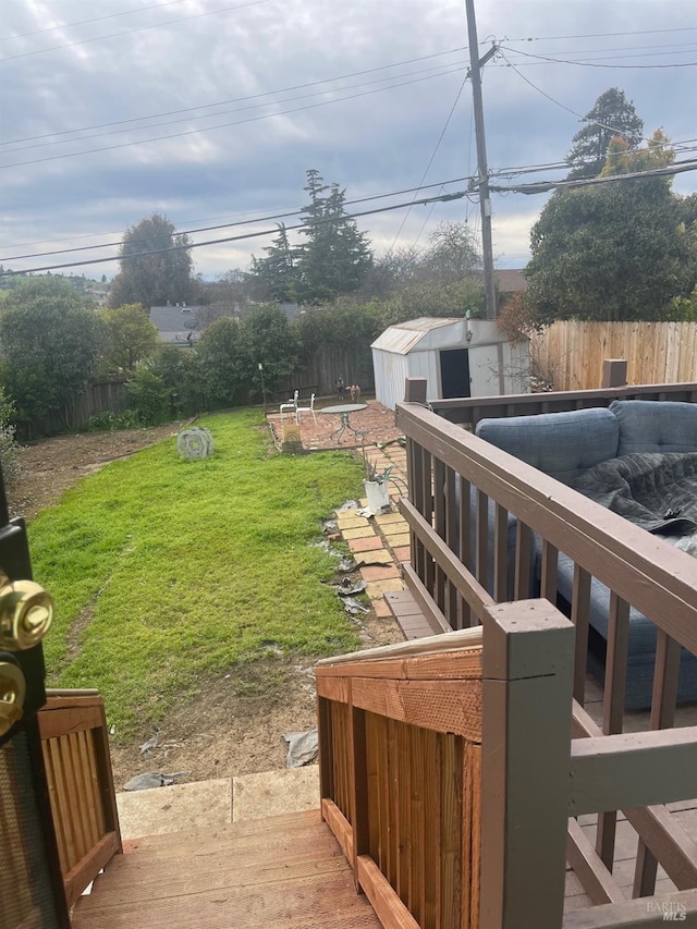 view of yard with a wooden deck, a storage unit, an outbuilding, and a fenced backyard