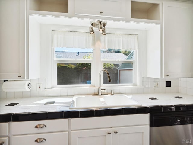 kitchen with a sink, tasteful backsplash, white cabinets, dishwasher, and tile counters