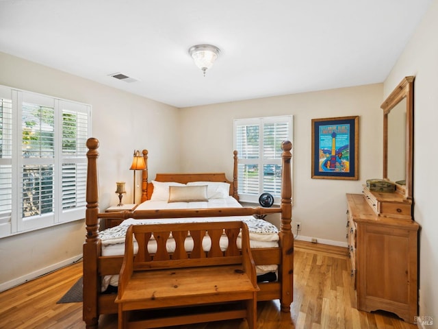 bedroom featuring baseboards, multiple windows, visible vents, and light wood-style flooring