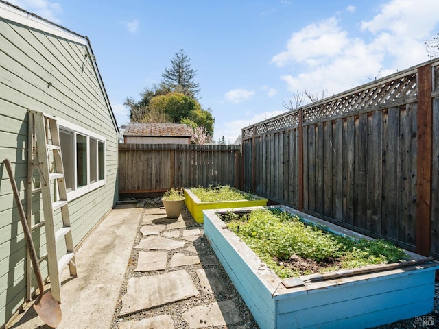 view of yard with a garden, a fenced backyard, and a patio area