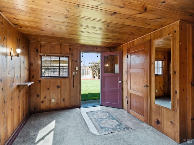 entryway featuring light carpet, wooden walls, wooden ceiling, and plenty of natural light