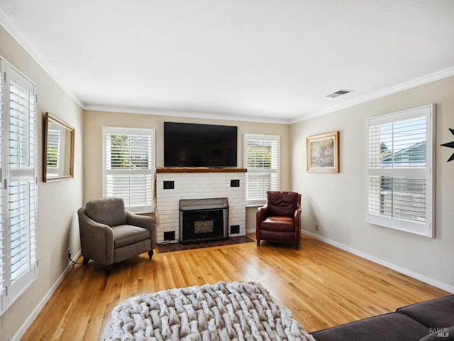 living area with a fireplace, wood finished floors, visible vents, and a healthy amount of sunlight