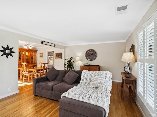 living area with visible vents, ornamental molding, baseboards, and wood finished floors