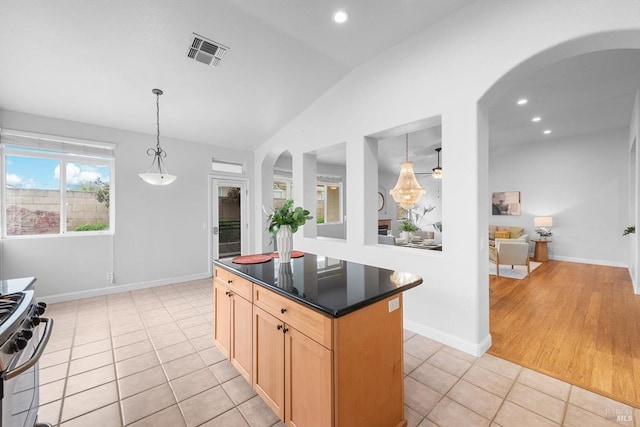 kitchen with vaulted ceiling, light tile patterned floors, stainless steel gas stove, arched walkways, and visible vents