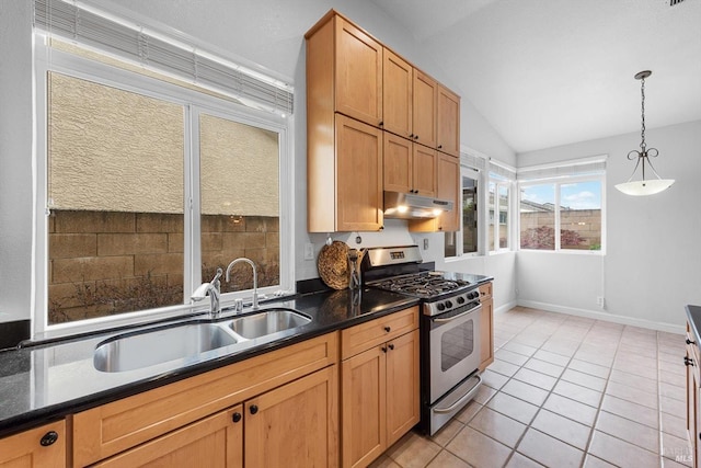 kitchen with stainless steel gas range oven, light tile patterned floors, under cabinet range hood, a sink, and dark countertops