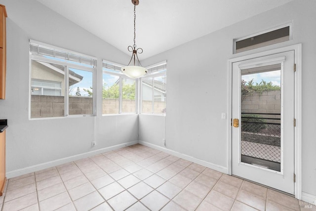 unfurnished dining area with light tile patterned floors, baseboards, and vaulted ceiling
