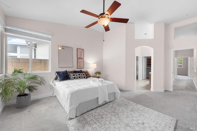 carpeted bedroom featuring multiple windows, arched walkways, and baseboards
