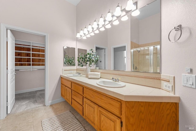 bathroom featuring double vanity, a sink, tile patterned floors, and a shower stall