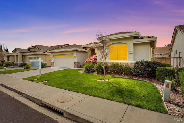 view of front facade with driveway, stucco siding, an attached garage, a tiled roof, and a yard