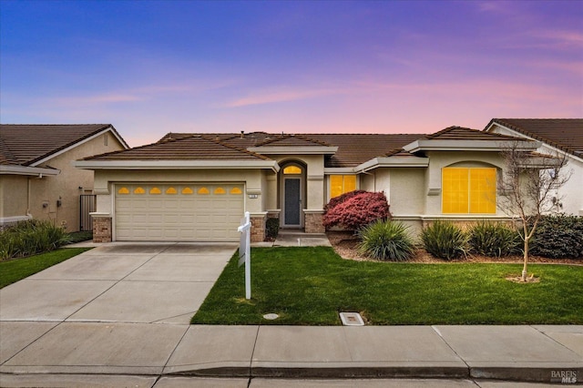 view of front of home featuring stucco siding, a tiled roof, concrete driveway, and a yard
