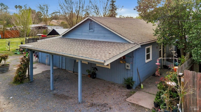 exterior space featuring fence and a shingled roof