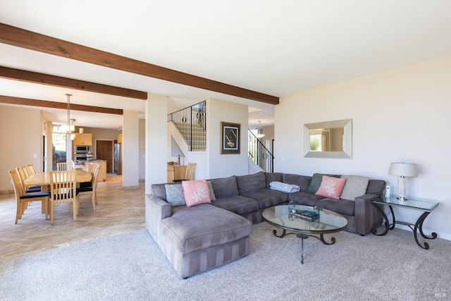 living area featuring beamed ceiling, light carpet, a notable chandelier, and stairs
