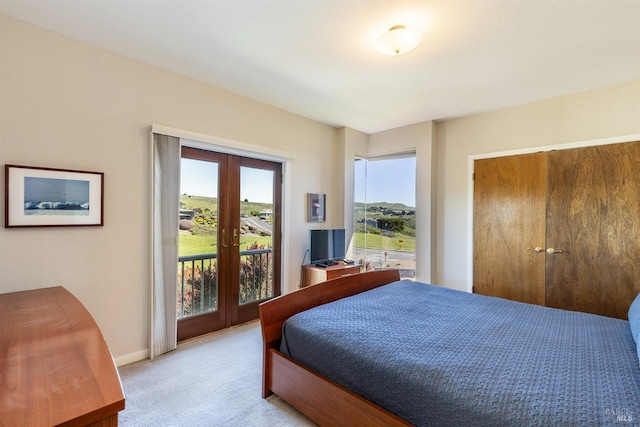 bedroom with light carpet, access to outside, french doors, a closet, and baseboards