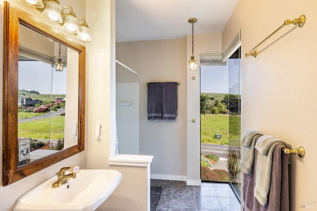 bathroom with tile patterned floors, plenty of natural light, baseboards, and a sink