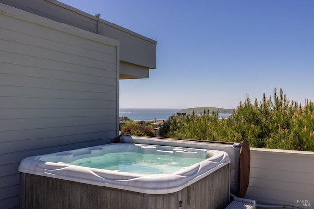 exterior space with a water view and a hot tub