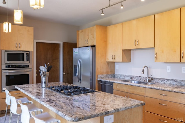 kitchen with a kitchen island, light brown cabinetry, a breakfast bar area, appliances with stainless steel finishes, and a sink