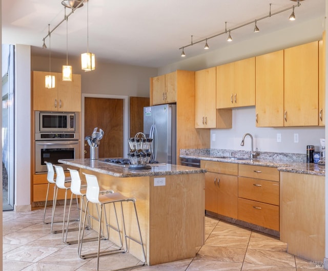 kitchen with light brown cabinets, a sink, a kitchen breakfast bar, stainless steel appliances, and stone counters