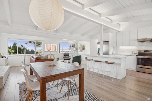 dining area featuring lofted ceiling with beams and light wood-style floors
